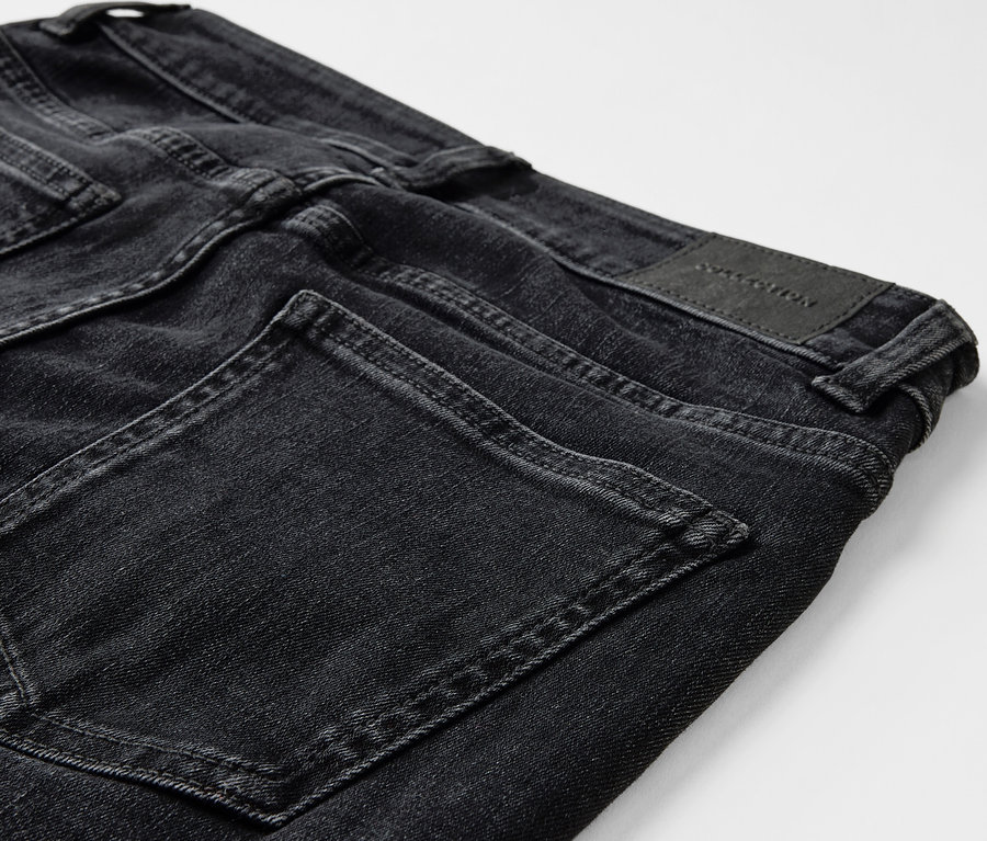 Gros plan sur un jean noir avec des poches et un patch en cuir à l'arrière.