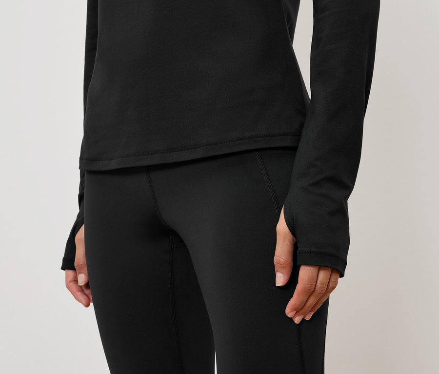 Gros plan d'une tenue de sport noire pour femme avec un haut à manches longues et un legging.