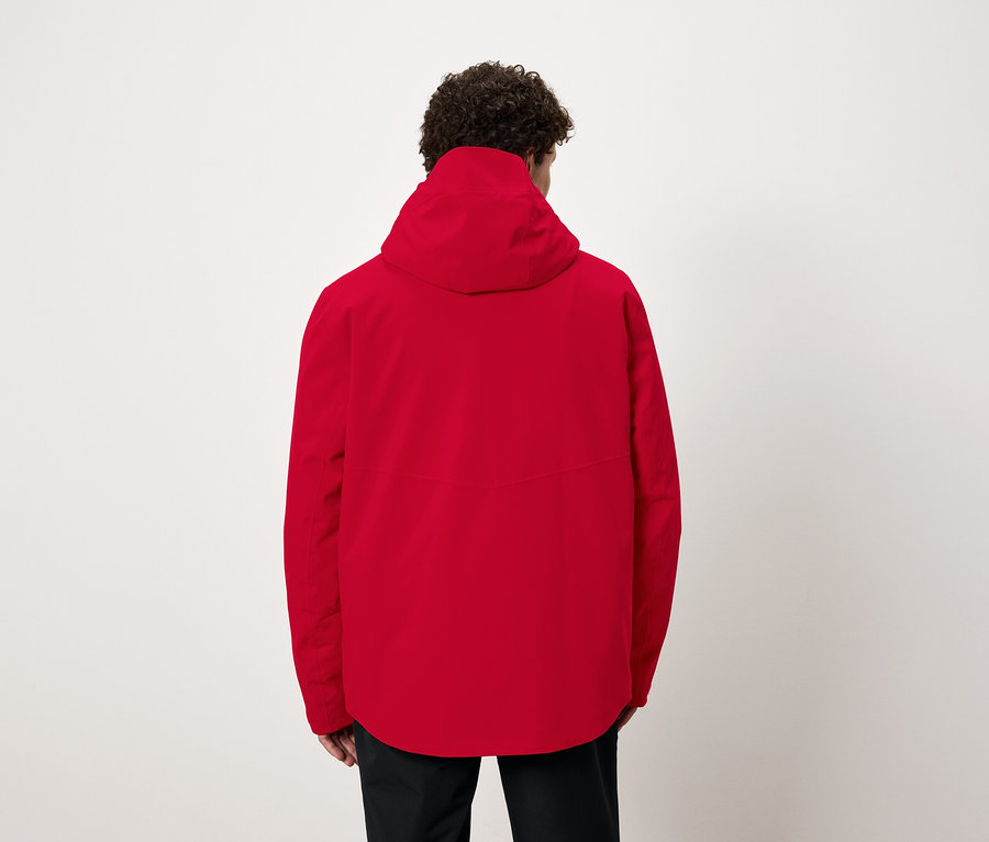 Un homme, vu de dos, porte une veste rouge à capuche.