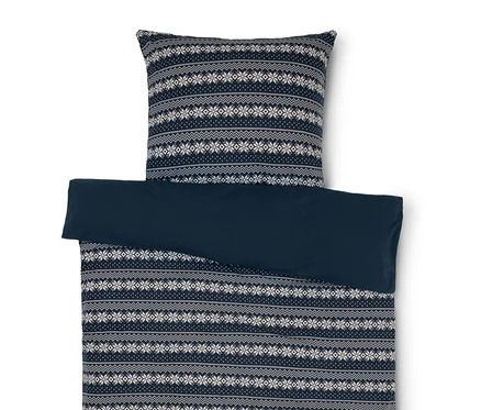 Linge de lit avec motif de flocons de neige bleu et blanc et drap bleu uni.