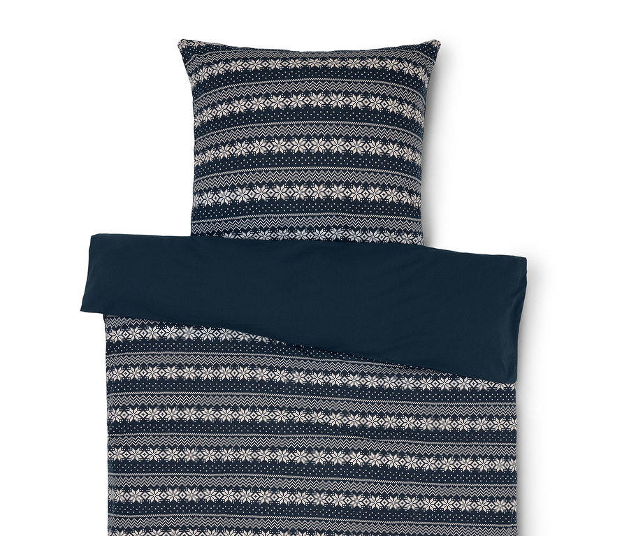 Linge de lit avec motif de flocons de neige bleu et blanc et drap bleu uni.