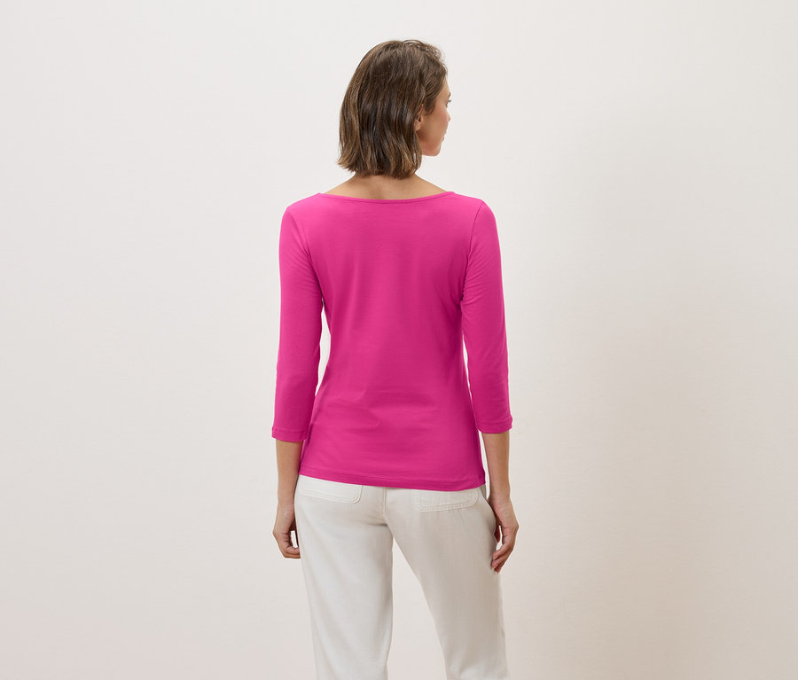 Vue arrière d'une femme aux cheveux bruns courts portant un t-shirt rose à manches trois-quarts et un pantalon blanc.