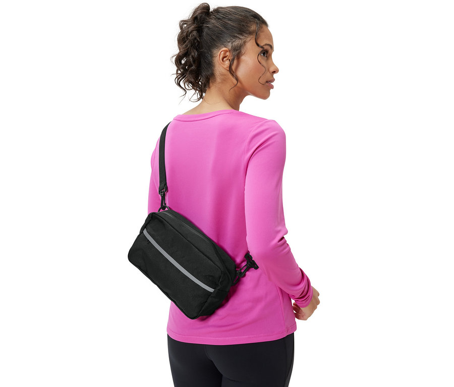 Une femme porte une sacoche de guidon 2 en 1 noire sur l'épaule.