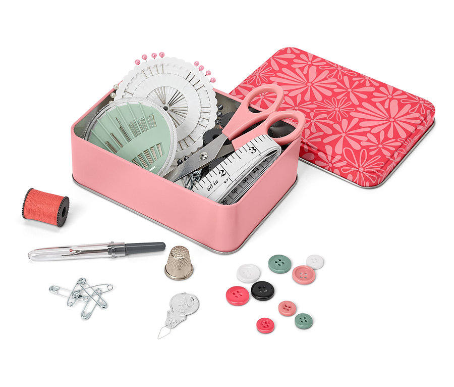 Boîte en métal ouverte contenant un kit de couture, à côté d'une bobine de fil, d'un dé à coudre, d'épingles, de boutons et d'un enfile-aiguille.