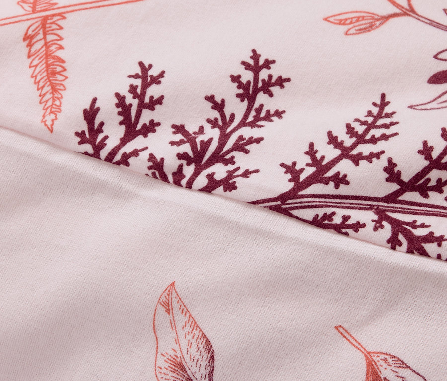 Gros plan d'un tissu avec un motif de feuilles et de branches dans les tons rose et bordeaux.