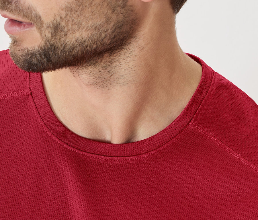 Gros plan d'un homme barbu portant un t-shirt bordeaux.