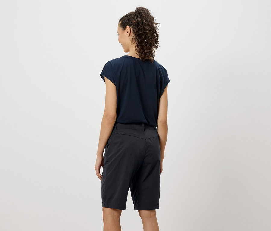 Vue arrière d'une femme aux cheveux bouclés portant un t-shirt bleu marine et un short.