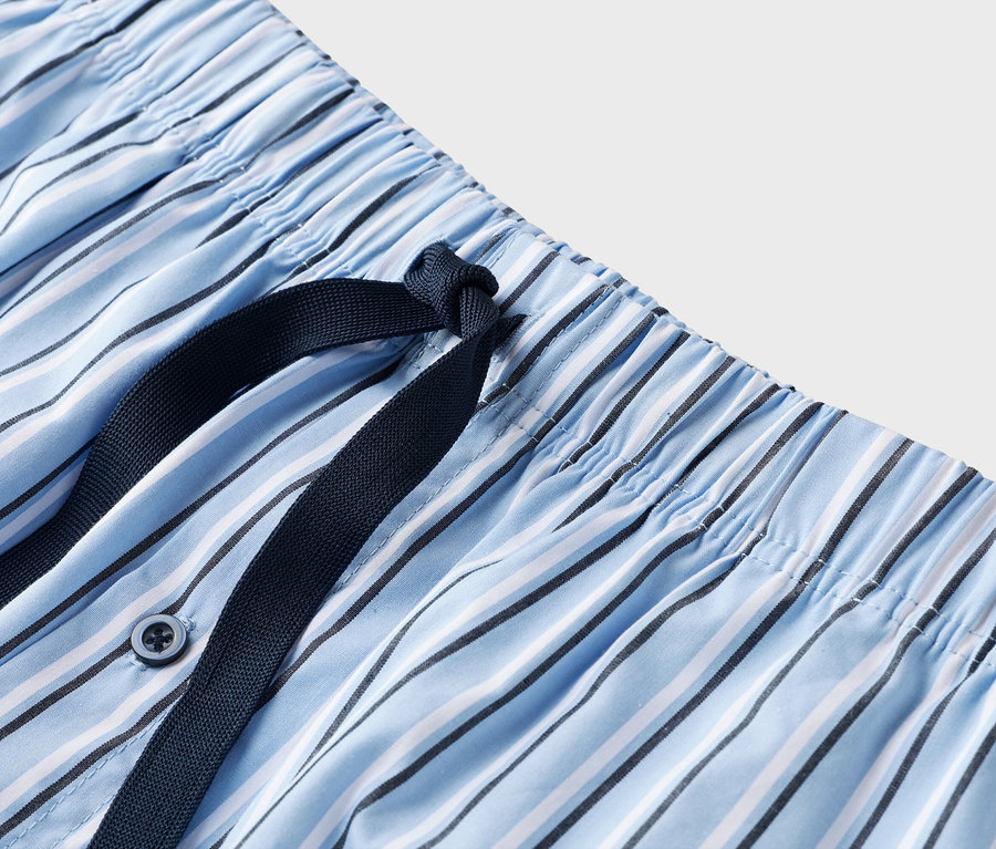 Gros plan sur le cordon bleu marine d'un pantalon de pyjama rayé bleu et blanc.