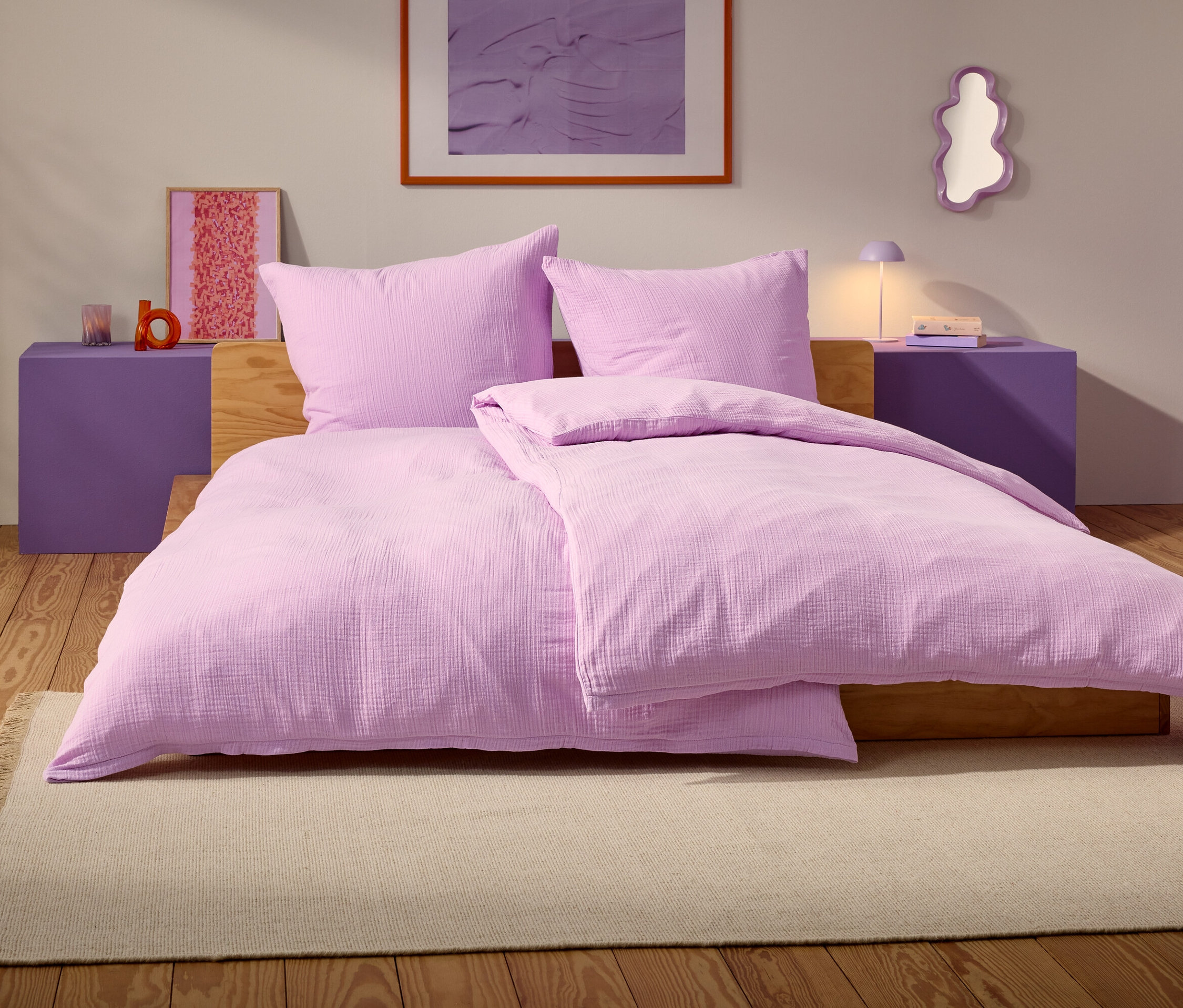 Un lit violet avec deux oreillers et une couverture se trouve sur un tapis beige dans une chambre.