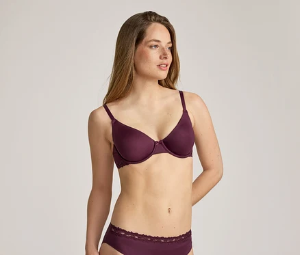Femme aux longs cheveux bruns portant un soutien-gorge bordeaux et des sous-vêtements assortis avec des finitions en dentelle.