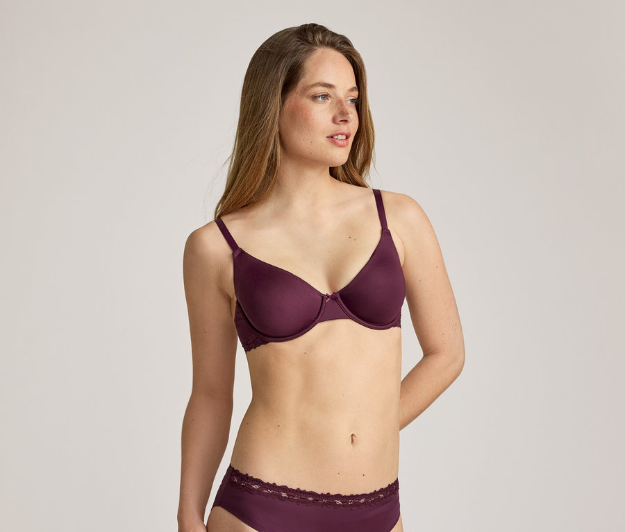 Femme aux longs cheveux bruns portant un soutien-gorge bordeaux et des sous-vêtements assortis avec des finitions en dentelle.