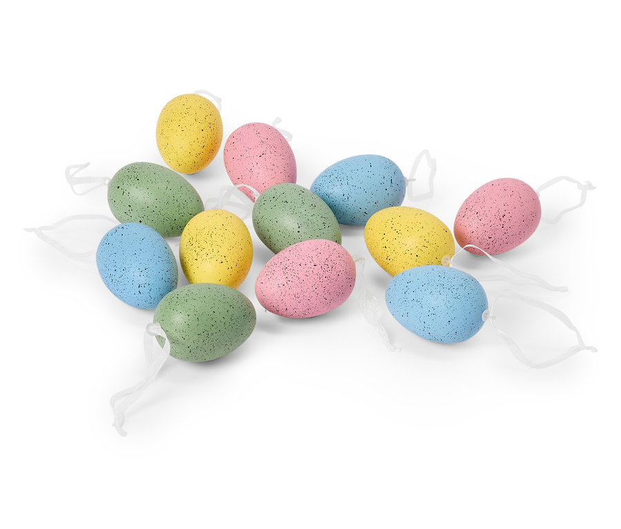 Une douzaine d'œufs de Pâques pastel avec des rubans blancs sont posés sur un fond blanc.