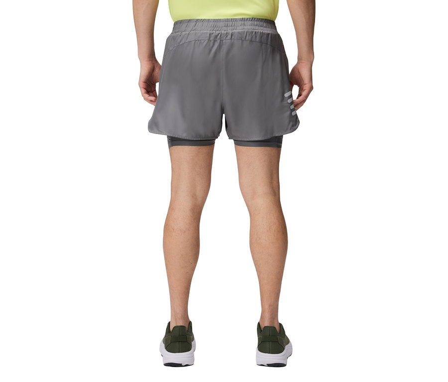 Un homme vu de dos portant un short gris et des chaussures vertes.