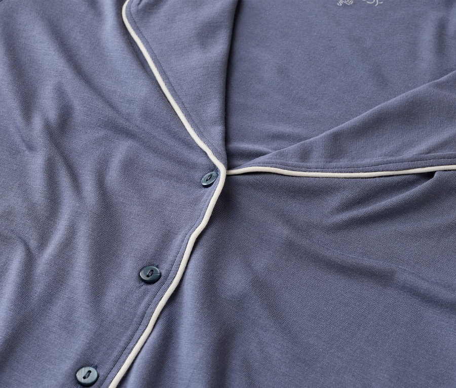 Gros plan sur un haut de pyjama bleu avec des passepoils blancs et des boutons.
