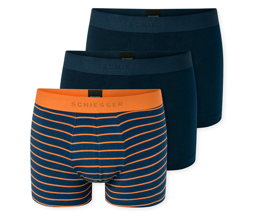 Trois boxers SCHIESSER empilés: le devant est bleu marine à rayures orange avec une ceinture orange, tandis que les deux derrière sont bleu marine uni avec des ceintures bleues.