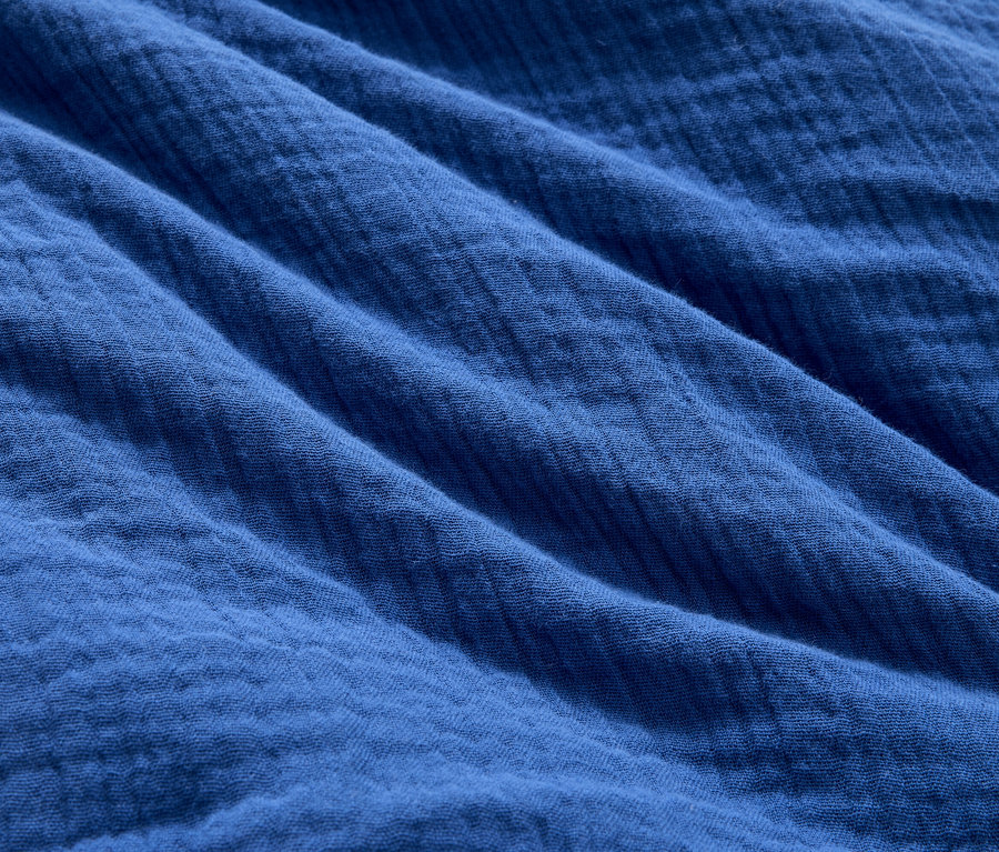 Gros plan d'un tissu en mousseline bleue avec des plis.