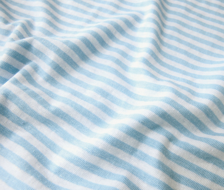 Gros plan d'un tissu rayé bleu clair et blanc, disposé en plis.