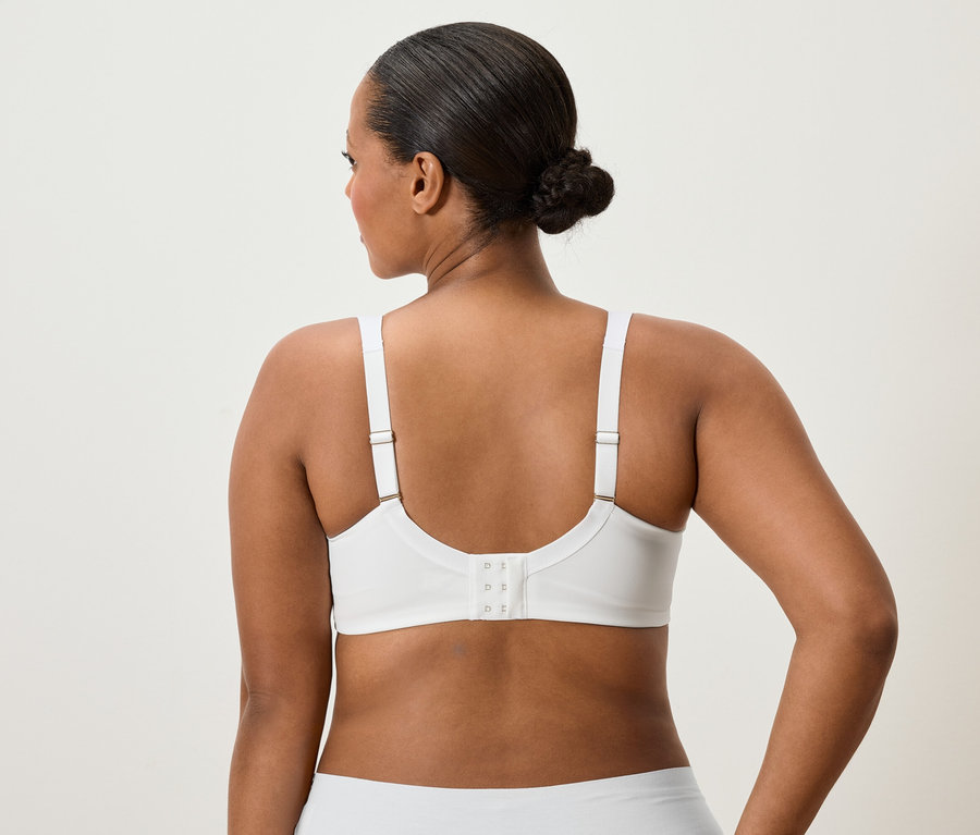 Vue de dos d'une femme avec un chignon portant un soutien-gorge et des sous-vêtements blancs.