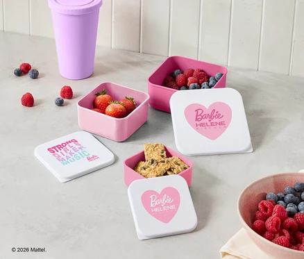 Sur un comptoir de cuisine, des récipients roses contenant des fraises, des framboises, des bleuets et des biscuits sont disposés à côté d'une tasse violette et d'un bol de baies.