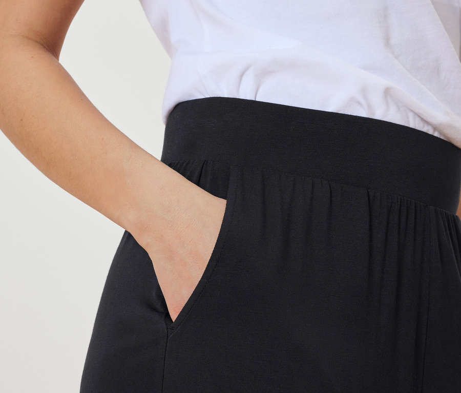 Femme mettant sa main dans la poche d'un pantalon noir