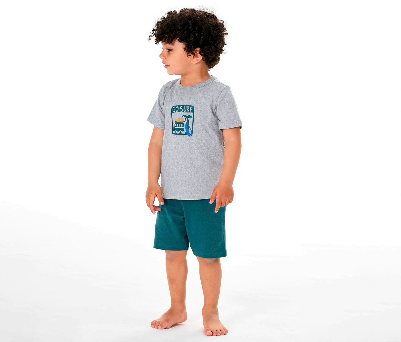 Garçon debout pieds nus en pyjama court pour enfant SCHIESSER avec motif de surf.