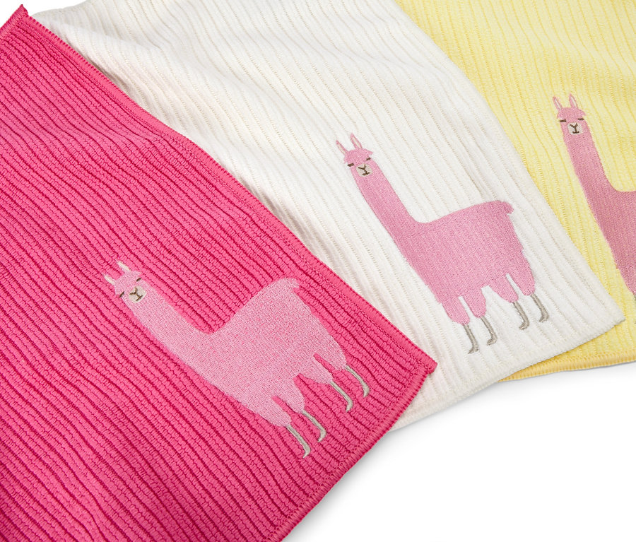 Trois gants de toilette roses, blancs et jaunes sont placés côte à côte, chacun avec un lama rose brodé.