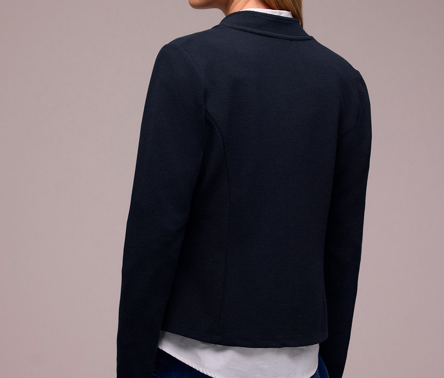 Femme de dos, légèrement tournée vers la droite, portant un blazer en jersey Street One bleu foncé sur une chemise blanche et un jean bleu.