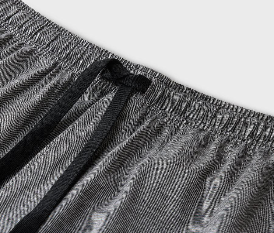 Gros plan d'un pantalon gris avec une taille élastique et un cordon de serrage noir.