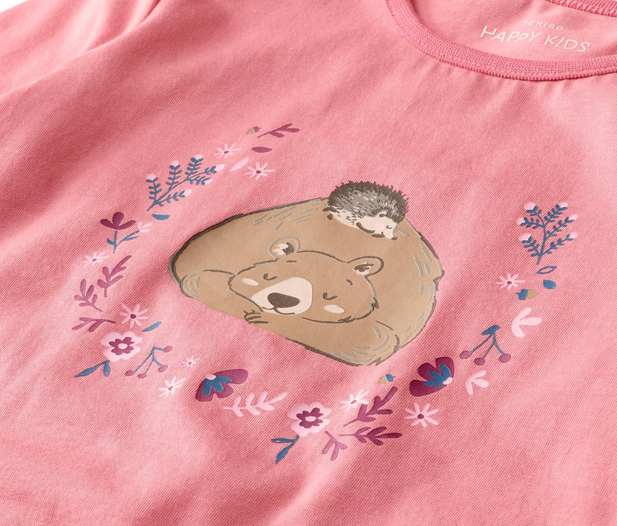 Sur un t-shirt rose, un ours endormi avec un hérisson sur le dos, entouré de fleurs.