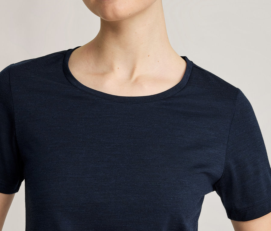 Gros plan d'une personne portant un t-shirt bleu foncé à manches courtes et col rond.