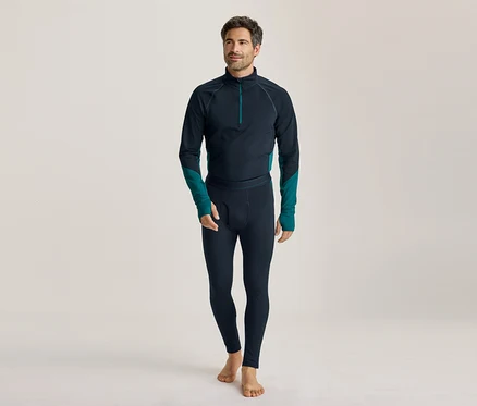 Homme pieds nus portant un haut à manches longues bleu foncé avec des accents turquoise et un legging assorti, regardant vers la gauche.