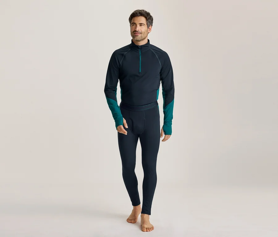 Homme pieds nus portant un haut à manches longues bleu foncé avec des accents turquoise et un legging assorti, regardant vers la gauche.