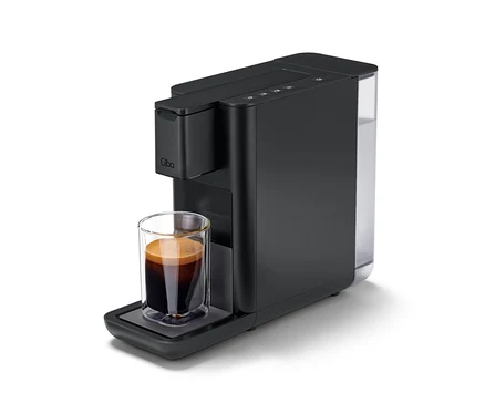Une machine à café Qbo ICONIC Dark Chrome avec une tasse de café.