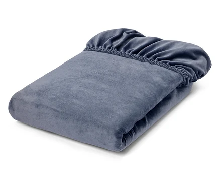Un drap-housse bleu-gris plié, en tissu velours doux, avec son bord élastique visible sur le dessus.