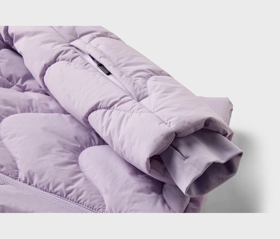 Gros plan d'une manche de veste matelassée lilas avec un poignet côtelé et une petite poche zippée.