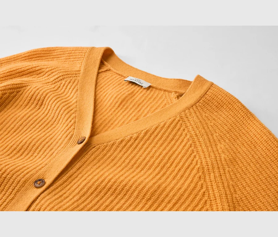 Cardigan en maille côtelée jaune moutarde avec col en V et deux boutons marron. Une étiquette blanche 'MYSTYLE' est visible à l'arrière du cou.