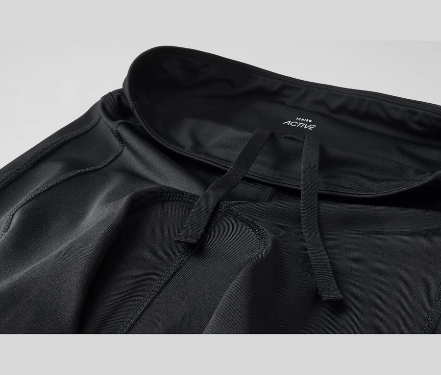 Pantalon de sport noir avec cordon de serrage et coutures apparentes. Le logo Tchibo Active est visible sur la ceinture.