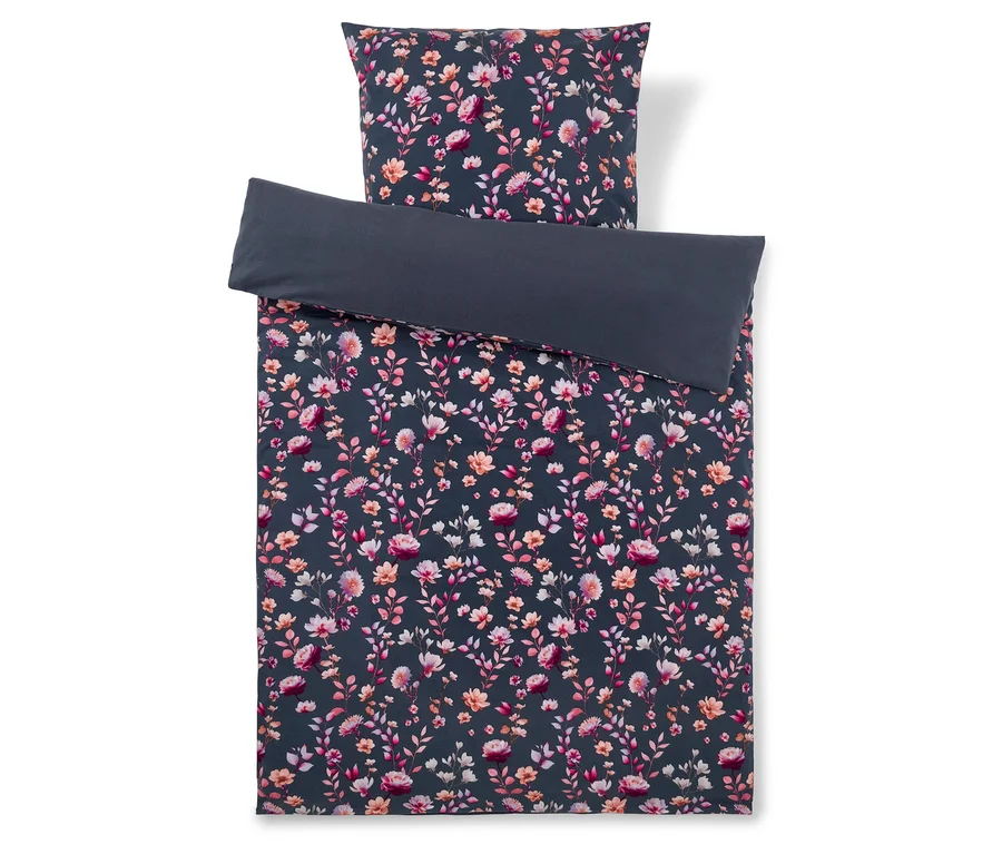 Housse de couette gris foncé avec un motif de fleurs et de feuilles roses, oranges et blanches, accompagnée d'une taie d'oreiller florale assortie et d'une taie d'oreiller gris foncé unie pliée dessus.