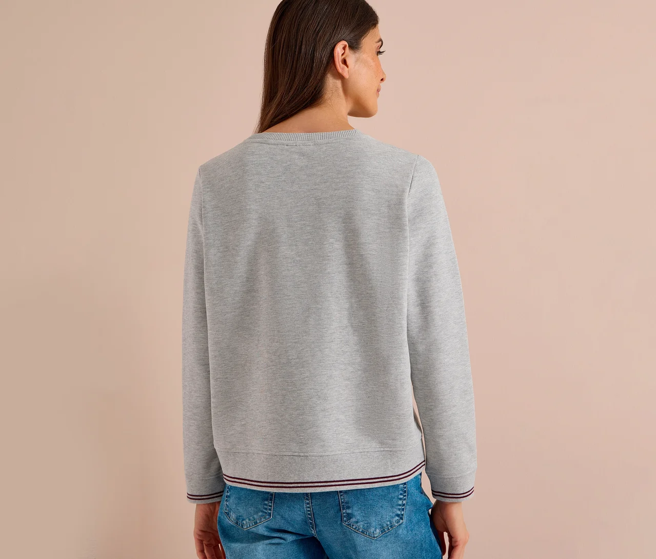 Femme vue de dos portant un sweatshirt CECIL gris avec un ourlet et des poignets côtelés rayés, associé à un jean bleu.