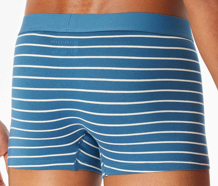 Un homme pose en boxer bleu rayé blanc.