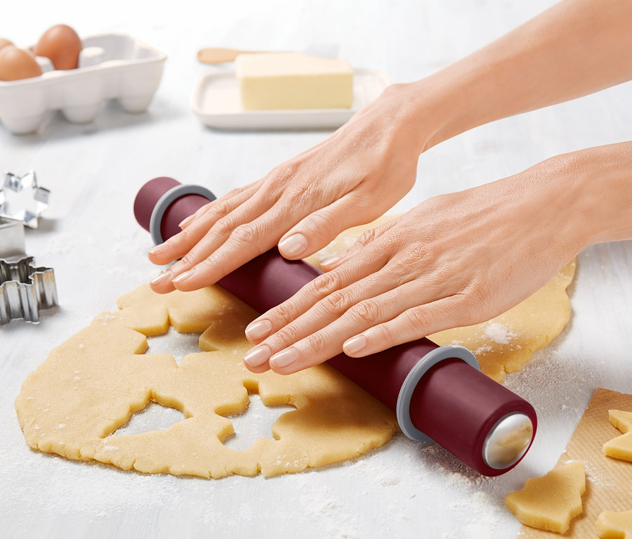 Femme abaissant la pâte à biscuits avec un rouleau à pâtisserie.