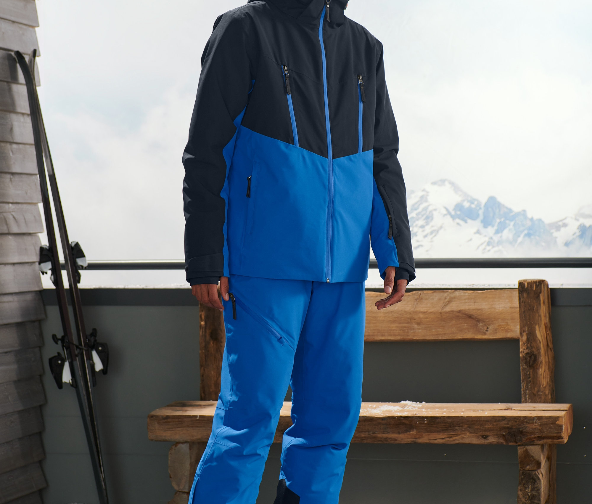 Un homme se tient à l'extérieur et porte une veste de ski bleue.