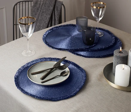 Table dressée avec 4 sets de table bleu-lilas, assiette et couverts.