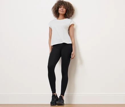 Une femme debout portant un legging de sport, un t-shirt et des baskets.