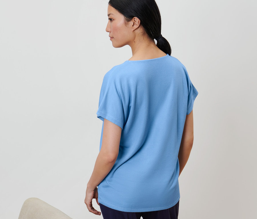 Femme portant une blouse structurée bleu clair.