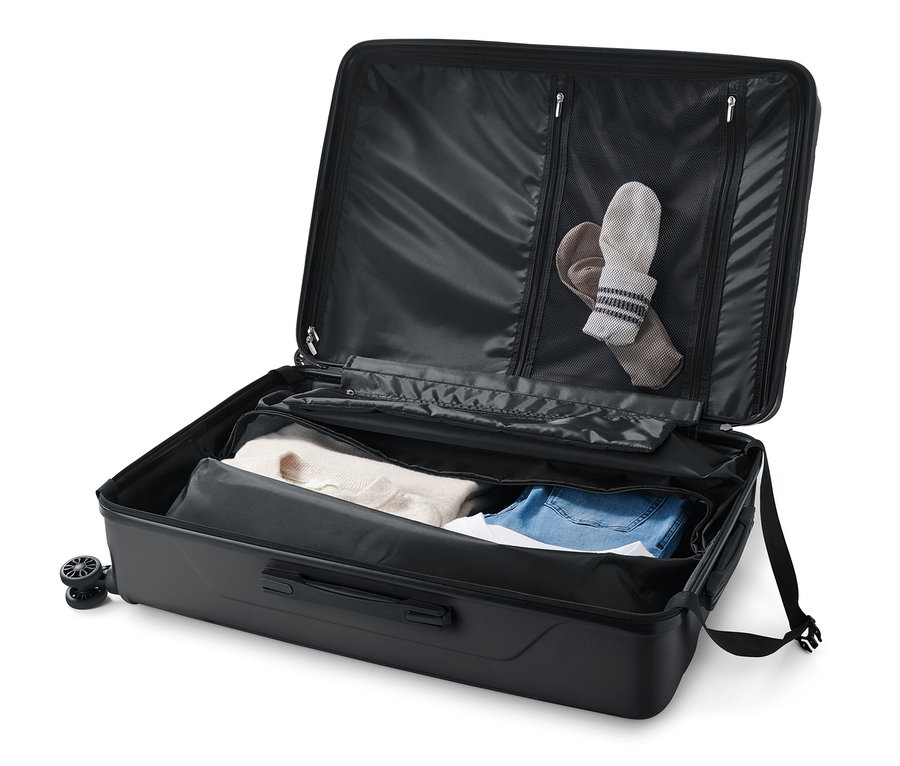 Valise rigide ouverte, grande, avec des vêtements à l'intérieur.