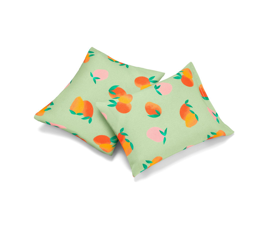 Deux coussins rafraîchissants avec un motif de pêches sur un fond vert clair.