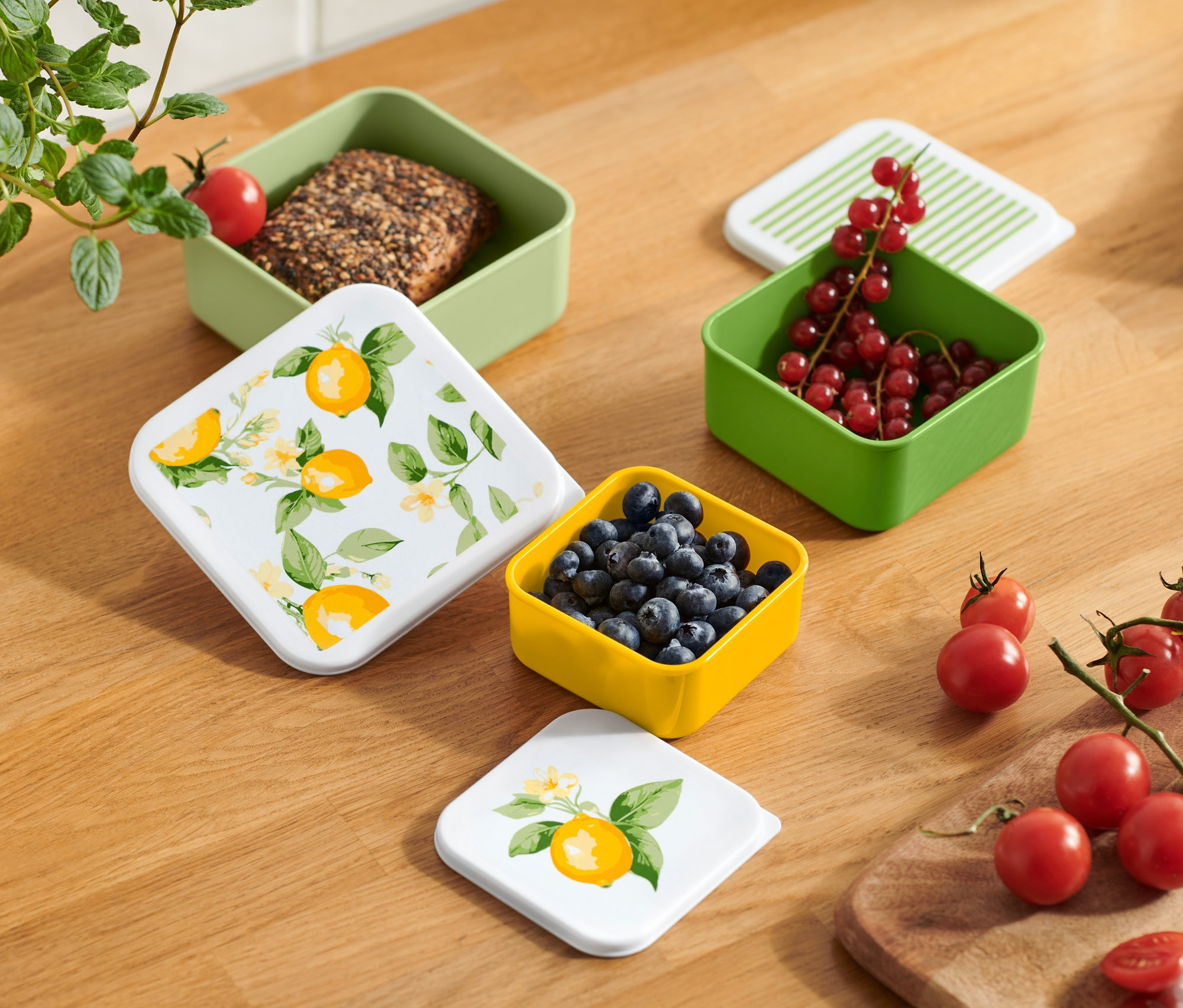 Vue de dessus d'une table en bois avec des boîtes à goûter de différentes couleurs contenant des fruits et des légumes.