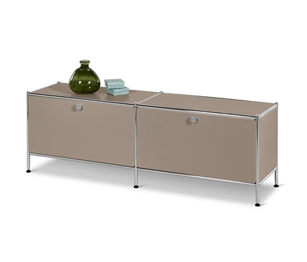 Un meuble bas en métal « CN3 » à 2 abattants, taupe. Sur le dessus, il y a un vase vert et deux petites boîtes.