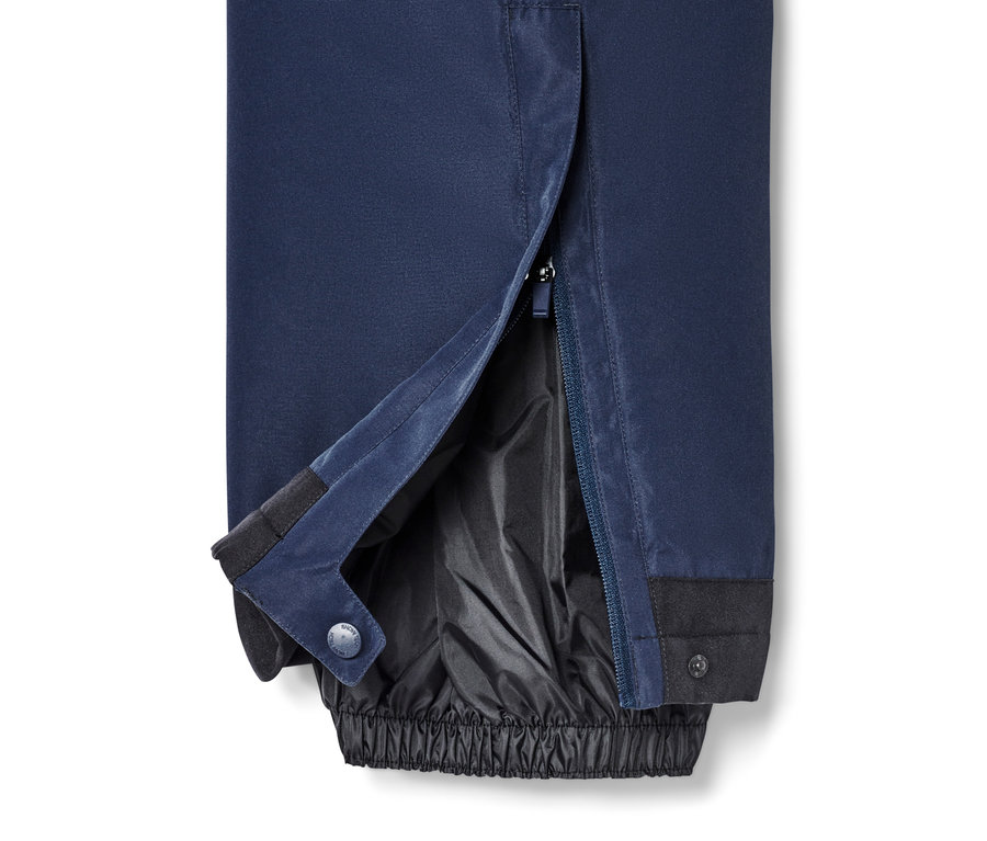 Gros plan sur un pantalon de ski bleu avec une fermeture éclair ouverte sur la jambe.